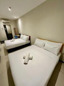 a hotel room with two beds and a cross on the bed at Swing & Pillows PJ Sunway Mentari formerly known as Swan Cottage Hotel in Petaling Jaya