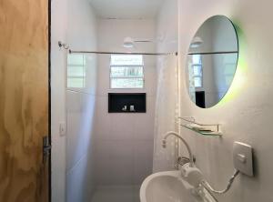 a white bathroom with a sink and a mirror at Casa Fofa! No Coração de Araras! in Araras Petropolis