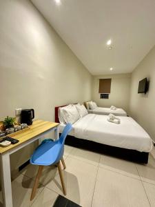 um quarto com uma cama, uma secretária e uma cadeira azul em Swing & Pillows PJ Sunway Mentari formerly known as Swan Cottage Hotel em Petaling Jaya