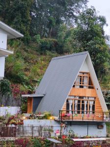 une maison avec un toit en gambrel et une terrasse couverte dans l'établissement Zangmo Lee Baam Rezay gangtok Sikkim, à Gangtok
