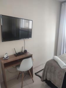 a bedroom with a desk with a television on a wall at Quarto na região central com alexa integrada e sacada in Curitiba