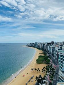 a beach with palm trees and the ocean and a city at Brisa Mar in Vila Velha