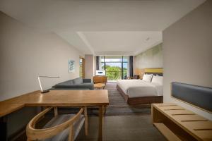 Habitación de hotel con cama y escritorio con TV. en Holiday Inn Express Emei Mountain, an IHG Hotel, en Emeishan