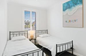 2 bedden in een witte kamer met een raam bij Penthouse Esplanade Cowes - Beach Front - Sea View in Cowes