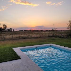 una piscina en un campo con la puesta de sol en el fondo en Almendra en Gómez