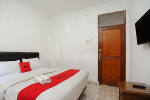 een slaapkamer met een bed met een rode en witte deken bij RedDoorz syariah near AEON Mall Tanjung Barat in Jakarta