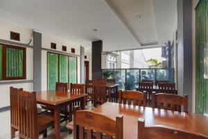 een restaurant met houten tafels, stoelen en ramen bij RedDoorz syariah near AEON Mall Tanjung Barat in Jakarta