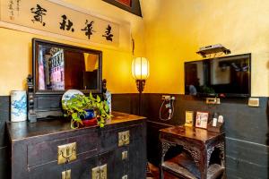 Pingyao Ji Family Courtyard Inn في بينغياو: غرفة معيشة مع تلفزيون وطاولة سيد