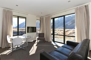 een woonkamer met een bank en een tafel en stoelen bij Aoraki Court Motel in Mount Cook Village