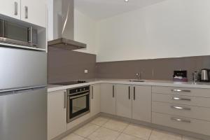 a kitchen with white cabinets and silver appliances at Aoraki Court Motel in Mount Cook Village