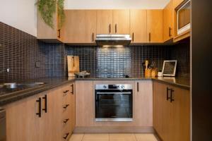 a kitchen with wooden cabinets and a sink and a stove at La Ronde One - Unit 1 - oceanstays in Yamba