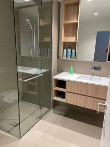 een badkamer met een glazen douche en een wastafel bij Experience Melbourne in Styles in Melbourne