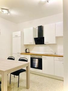 a kitchen with white cabinets and a table with chairs at Luxury Premium Apartments in Bonn