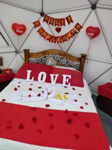 a bed with red hearts and the words love at Hotel Campestre Mirador De San Nicolas in Ubaque