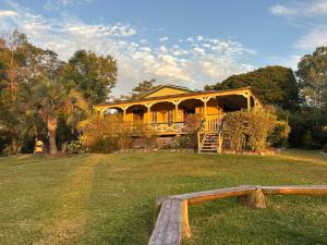 a large yellow house with a porch on a field at Noosa Hinterland Escape in Black Mountain