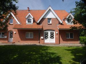 une maison en briques avec un toit orange dans l'établissement Haus-Am-Sommerdeich-Whg-02, à Sankt Peter-Ording