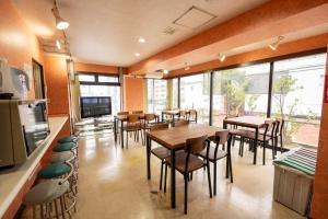 a restaurant with tables and chairs in a room at ユースホステルソノママ in Kofu