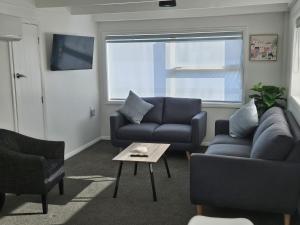 a living room with two couches and a table at Redwood Apartments in Rotorua