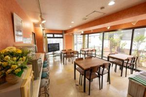 a restaurant with tables and chairs and a television at ユースホステルソノママ in Kofu