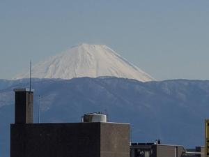 a snow covered mountain in the distance behind a building at ユースホステルソノママ in Kofu