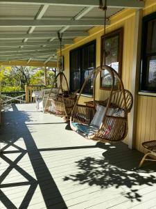 um alpendre com três cadeiras de baloiço num edifício em Noosa Hinterland Escape em Black Mountain