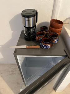 a shelf with a coffee maker and bowls on it at Cuarto chingui in Holbox Island