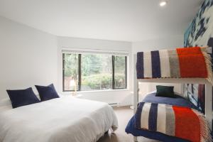 a white bedroom with a bed and a window at The Blackcomb Ski-In Getaway in Whistler