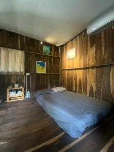 a bed in a room with a wooden wall at Cactos Bar & Homestay in Ho Chi Minh City