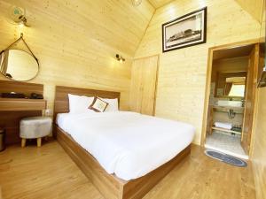 a bedroom with a bed in a wooden room at Kim Resort - Khu Nghĩ Dưỡng Rừng Lá Kim in Da Lat