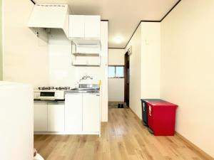 una cocina con armarios blancos y un cubo de basura rojo en House Kadoi201, en Tokio