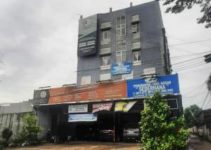 a tall building with a sign in front of it at RedDoorz Syariah At Penginapan Sederhana Palembang in Palembang