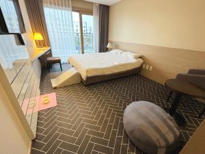 Habitación de hotel con cama y silla en The Best Jeju Seongsan, en Seogwipo