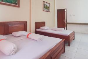a room with three beds in a room at RedDoorz Syariah At Penginapan Sederhana Palembang in Palembang
