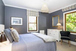 a blue bedroom with a bed and a chair at Stags Head Cottage-cosy cottage with hot tub in Arrowtown