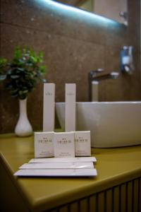 een badkamerbar met drie witte kaarten op een wastafel bij The House Hotel Yerevan in Jerevan