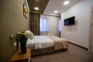een hotelkamer met een bed en een vaas met bloemen bij The House Hotel Yerevan in Jerevan