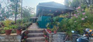 a small building with plants in a garden at Madhuvana Guest House in Madikeri