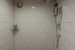 a shower with a blow dryer in a white tiled bathroom at V1 boutique hotel in Kanchanaburi