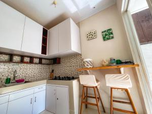 a kitchen with white cabinets and two bar stools at Villa Jogja Grand Bale with Private Pool by Simply Homy in Yogyakarta