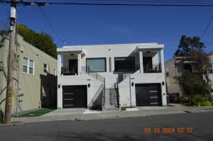 a white house with black garage doors on a street at Dimond Abode Vacation Home #2 Oakland Dimond District in Oakland