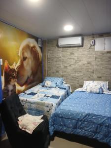 a bedroom with two beds and a painting of a dog and a cat at Apartamento frente al castillo San Felipe in Cartagena de Indias