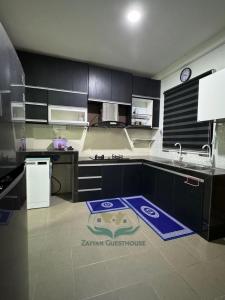 una cucina con armadi neri e un tappeto blu sul pavimento di Zayyan Guesthouse a Kuching