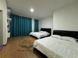 2 letti in una camera da letto con tende blu di Zayyan Guesthouse a Kuching