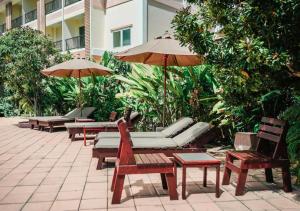 un patio con sillas, mesas y sombrillas en Savotel Hotel, en Na Jomtien