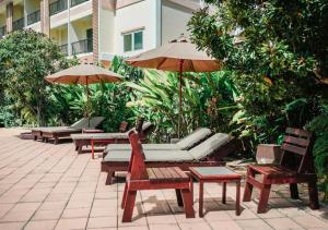 a patio with chairs and tables and umbrellas at Savotel Hotel in Na Jomtien