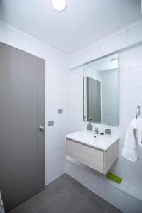 La salle de bains blanche est pourvue d'un lavabo et d'un miroir. dans l'établissement Te alojo Conce, Apart Hotel, à Concepción