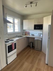 a kitchen with white cabinets and a stove and refrigerator at One bedroom entire unit in Christchurch