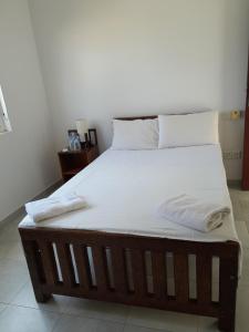 uma cama grande com lençóis brancos e almofadas em Amssler Beach Stay em Kalutara