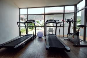 a gym with three treadmills in a room with windows at The Melody Phuket - SHA Extra Plus in Kata Beach