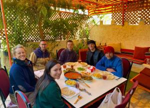 アカバにあるAl-Amer Hostelのテーブルの周りに座って食事をとる人々のグループ